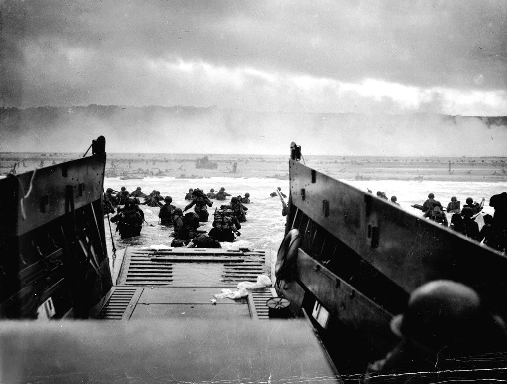 American soldiers wade from a landing craft toward Omaha Beach and the bluffs beyond on the morning of June 6, 1944.